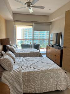 1 dormitorio con 2 camas, TV y ventana en Beachfront Condo DelCanto Resort, en Nuevo Vallarta 