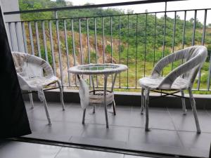 3 Stühle und ein Tisch auf einem Balkon mit Aussicht in der Unterkunft H&H Lovely Homestay in Nilai (Residensi Lili) in Nilai