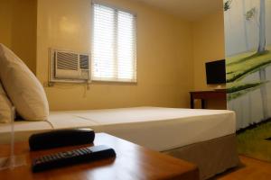 a bedroom with a white bed and a window at Spaces Hotel Makati in Manila