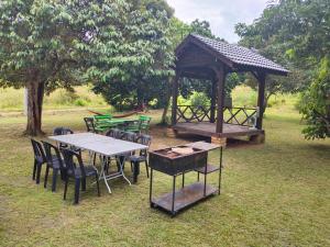 a picnic shelter with tables and chairs in a park at Homestay Kampung Den in Kampong Jimah