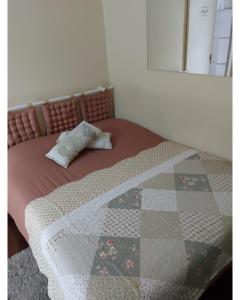 a bed with a quilt on top of it at Aluguel Temporada em Gramado in Gramado
