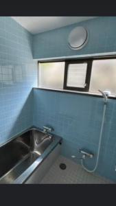 baño con lavabo y pared de azulejos azules en 桃源郷, en Hutami