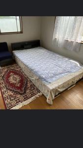 a bed in a corner of a room with a rug at 桃源郷 in Futami