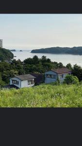 dwa domy siedzące na szczycie wzgórza z wodą w obiekcie 桃源郷 w mieście Hutami