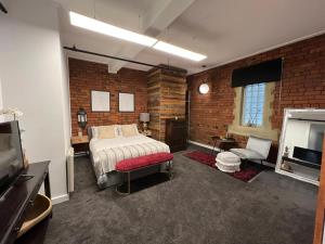 - une chambre avec un lit et un mur en briques dans l'établissement StayCentral - Heritage Warehouse Retreat Melbourne, à Melbourne