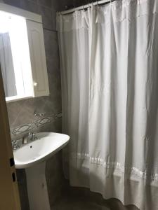 a bathroom with a white shower curtain and a sink at Comodo departamento centrico in San Pedro +2 photos