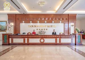 a lobby of a hotel with two people standing at a counter at Tan Son Nhat Saigon Hotel in Ho Chi Minh City