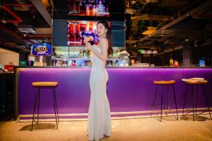 una mujer parada frente a una barra púrpura en SOJO Hotel Nam Dinh en Nam Ðịnh
