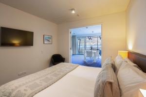1 dormitorio con 1 cama y TV en la pared en Absolute Lakefront Location - 3 bedroom apartment, en Queenstown