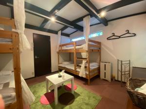 a room with two bunk beds and a table at Bamboo Village Guest House in Naoshima