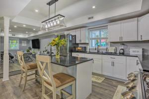 una cocina con armarios blancos y una isla con sillas en Stunning South Fallsburg Home with Pool and Deck!, 