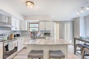 a kitchen with white cabinets and a large island with bar stools at Bright Toledo Duplex, Close to Parks and Trails in Toledo