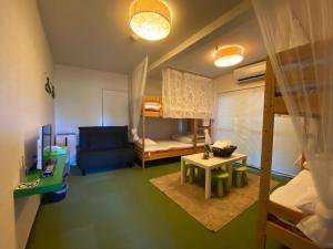 a small room with a bunk bed and a couch at Bamboo Village Guest House in Naoshima