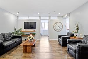 soggiorno con mobili in pelle nera e orologio di Bondi Breeze Apartments a Sydney