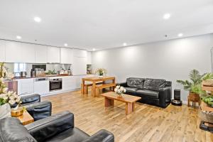 un soggiorno con mobili in pelle nera e una cucina di Bondi Breeze Apartments a Sydney