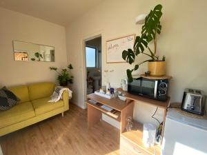 a living room with a yellow couch and a microwave at The Willow Guest Suite in Dunedin