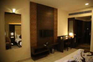 a hotel room with a television and a bedroom at WEST FORT HOTEL in Bangalore