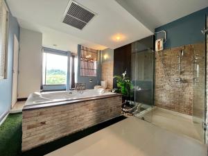 a bathroom with a large tub and a glass shower at โรงแรมวิลลา พาราดี in Ban Khanong Phra Tai