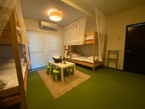 a small room with bunk beds and a table at Bamboo Village Guest House in Naoshima