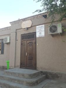 a building with a wooden door with a sign on it at Hotel Allanazar Ota in Khiva