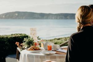 a woman sitting at a table with a plate of food at Cottage Pie by Robberg in Plettenberg Bay