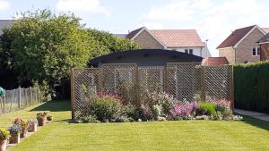 a fence in front of a yard with flowers at The Annexe, Cornfields in Elmswell