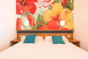 a bedroom with two beds and a painting of flowers at Apartments Palm Garden in front of the beach in Morro del Jable +33 photos