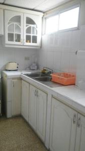 una cocina con armarios blancos y fregadero en Edificio El Constructor Apartamento Independiente, en Guayaquil