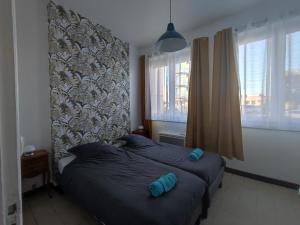 a bedroom with a bed with two blue pillows at Le Cottage Malouin in Dunkerque