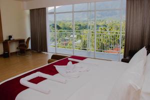 a bedroom with a white bed and a large window at Horison Sentani in Ifaar