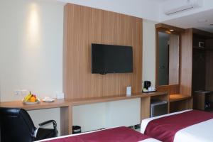 a hotel room with a desk with a television on a wall at Horison Sentani in Ifaar