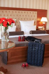 a hotel room with a bed with a table and a suitcase at Nadiya Hotel in Ivano-Frankivsk