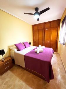 1 dormitorio con cama con sábanas moradas y almohadas moradas en Daniela apartament, en Torrevieja