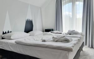 two white beds in a room with a window at Holimo Hotel in Stronie Śląskie