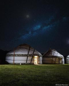 two large domes in a field at night at Ulush Yurts in Naryn