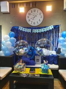 um quarto com um relógio e balões e uma mesa com um feliz aniversário em Palazzo 1 HotSpring,3Bedrooms 35to40pax, Pansol Calamba em Pansol
