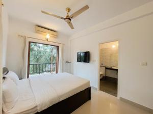 a white bedroom with a bed and a window at Rainforest - Casa Del Sol, Anjuna - 3 kms from the beach in Anjuna