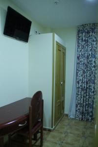 Habitación con mesa y TV en la pared. en Hotel Pizarro, en Humanes de Madrid