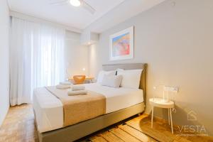 - une chambre avec un lit doté de draps blancs et une fenêtre dans l'établissement The Modern World Apartment, Vesta Philoxenia, à Thessalonique