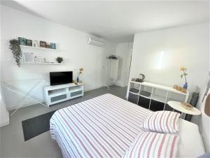 biała sypialnia z łóżkiem i telewizorem w obiekcie Plaza de toros / Centro w Maladze