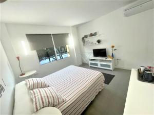 biała sypialnia z łóżkiem i telewizorem w obiekcie Plaza de toros / Centro w Maladze