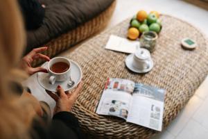 a woman holding a cup of tea on a coffee table at Dome Hotel in Riga