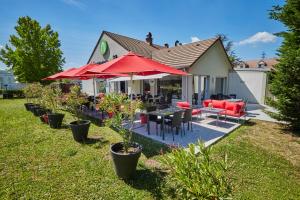 Campanile Evry Ouest - Corbeil Essonnes في كورباي إيسون: منزل به فناء مع مظلات حمراء