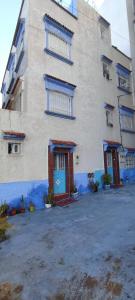 un grand bâtiment avec une porte bleue dans un parking dans l'établissement Mehdi House, à Chefchaouen