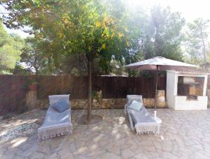 un patio con 2 sillas, una sombrilla y un árbol en INNOUTHOME A 100m de la playa Port de l'Estany II, en L'Ametlla de Mar