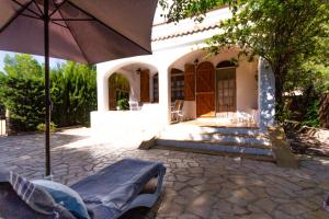 un patio con sombrilla frente a una casa en INNOUTHOME A 100m de la playa Port de l'Estany II, en L'Ametlla de Mar