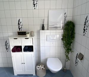 a bathroom with a toilet and a white tiled wall at Schöne Wohnung mit Terrasse & Blick ins Grüne in Dormettingen