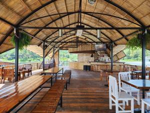 a restaurant with wooden tables and chairs and a large ceiling at บ้านไร่ วรรณ วาลย์ รีสอร์ท in Tha Kradan