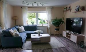 a living room with a blue couch and a tv at Schöne Wohnung mit Terrasse & Blick ins Grüne in Dormettingen