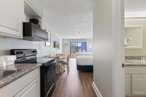 a kitchen and living room with a bed in a room at SeaMist Driftwood Vacation Studio with Balcony in Myrtle Beach